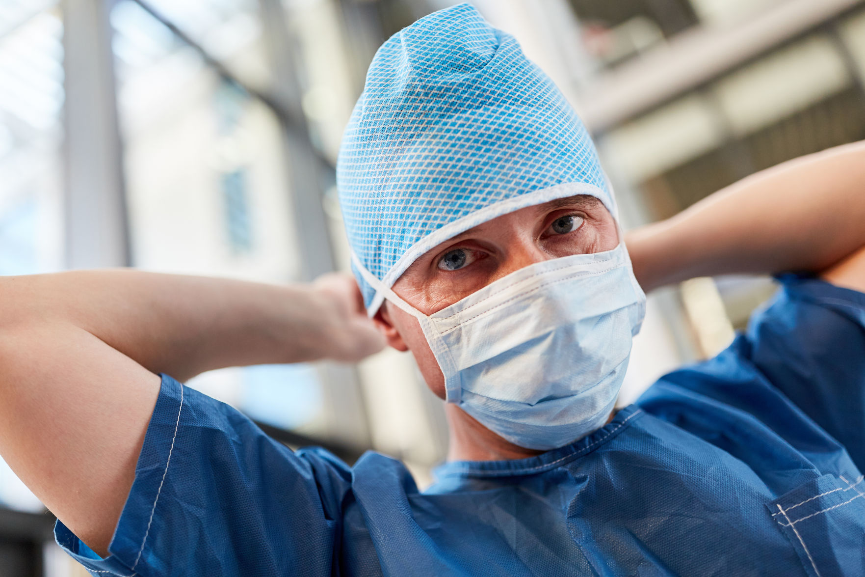 Doctor as a surgeon in the emergency room in blue surgical clothing with surgical mask and hood
